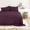 Luxurious deep purple bedroom bedding with matching pillow shams on a modern, minimalist bed setting.