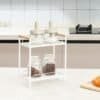 Minimalist white metal spice rack with glass jars on kitchen countertop.