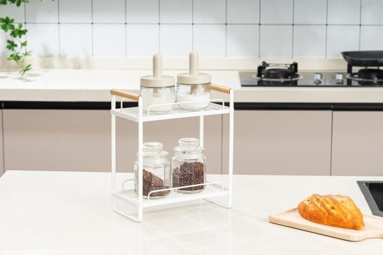 Minimalist white metal spice rack with glass jars on kitchen countertop.