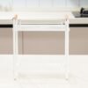 White kitchen dish drying rack with wood handles on a clean countertop.