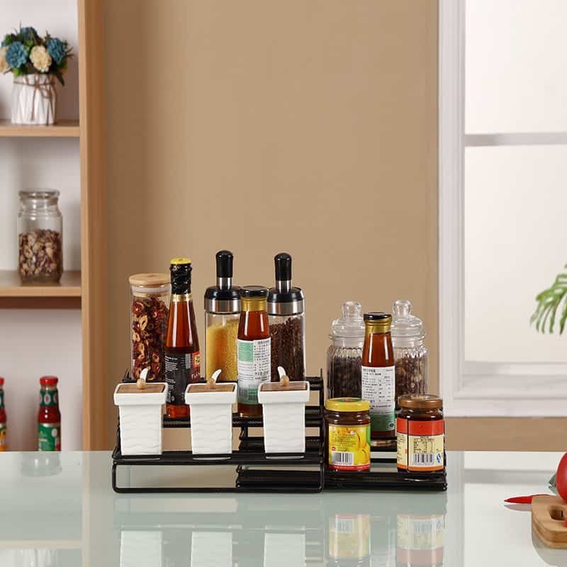 Organized spice rack with glass jars and condiment bottles on kitchen countertop.