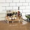 Stackable spice jars on a wooden kitchen countertop with a white tile backsplash, ideal for organized kitchen storage.