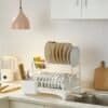 Elegant dish drying rack for kitchen, organized with plates, cups, and utensils. Modern kitchen design by Arsi Studio.