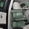 green leather back seat organizer with cup holder, tray table, and storage pockets.