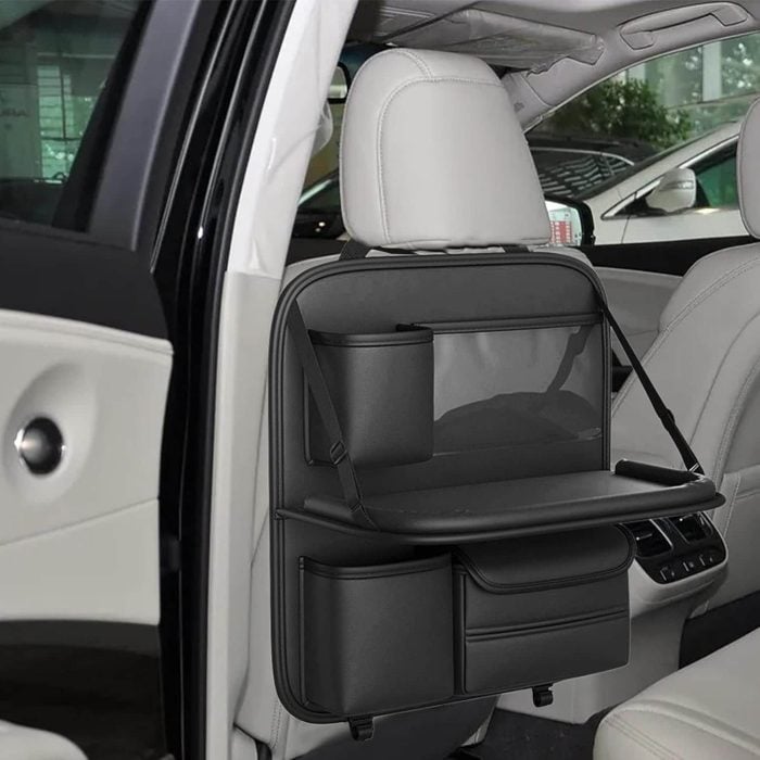Black leather back seat organizer with cup holder, tray table, and storage pockets.