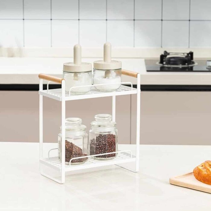 Minimalist white metal spice rack with glass jars on kitchen countertop.