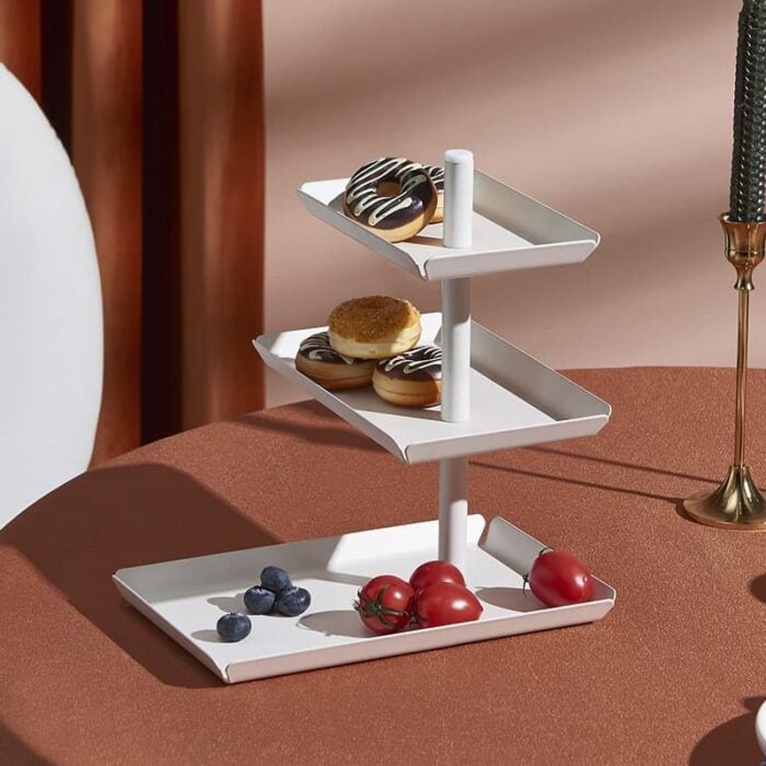 Deluxe multi-tiered dessert-serving stand with donuts and fresh tomatoes on a stylish table.